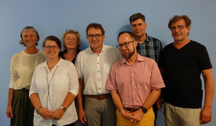 Gruppenfoto vor taubenblau gestrichener gewölbter Wand im Flurbereich mit Frau Wolfgramm, Ute Vogt, Frau Weiß, Herr Bernlöhr, Herr Uhl, Herr Roller und Herr Hegener