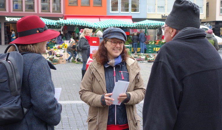 Ute Vogt im Gespräch mit einer Bürgerin und einem Bürger vor dem Hintergrund des Stuttgarter Markttreibens