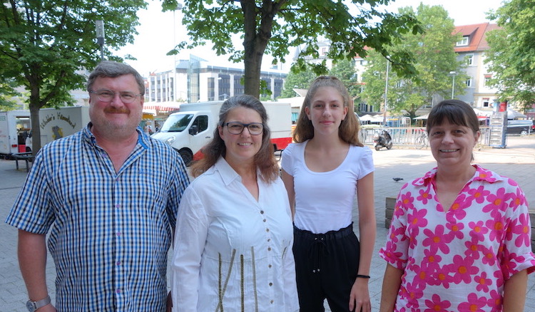 Lara Joyce, Ute Vogt und die beiden Mitarbeiter stehen auf dem Wilhelmsplatz, im Hintergrund ist Markttag.