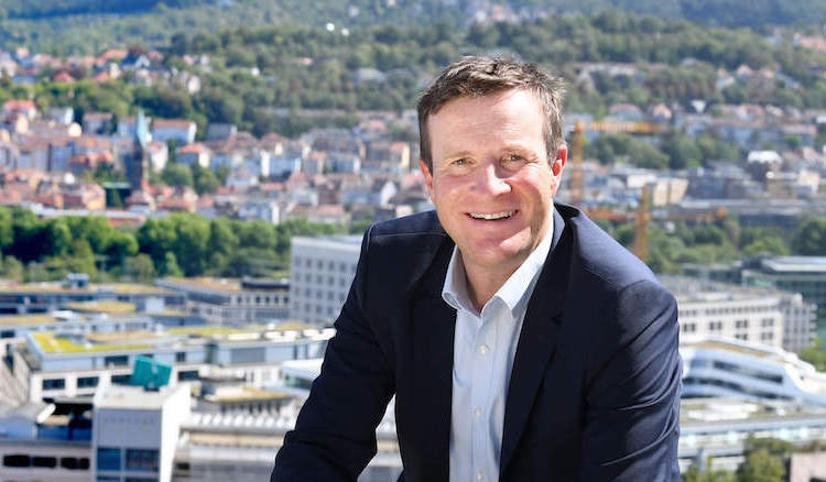 Martin Körner in Hemd und Sakko lächelt, im Hintergrund der Talkessel Stuttgarts