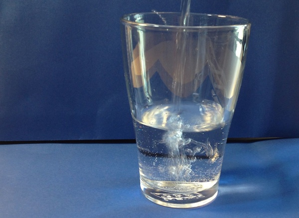 Glas wird mit Trinkwasser gefüllt
